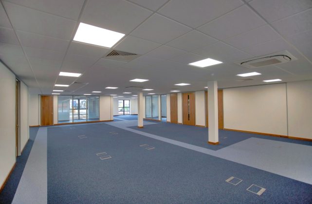 Empty office area with partitioned meeting rooms at the side